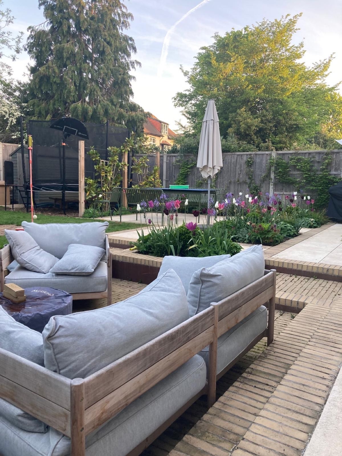The same terrace in spring — tulips through the raised beds, proving the planting plan works before the lawn has woken up.